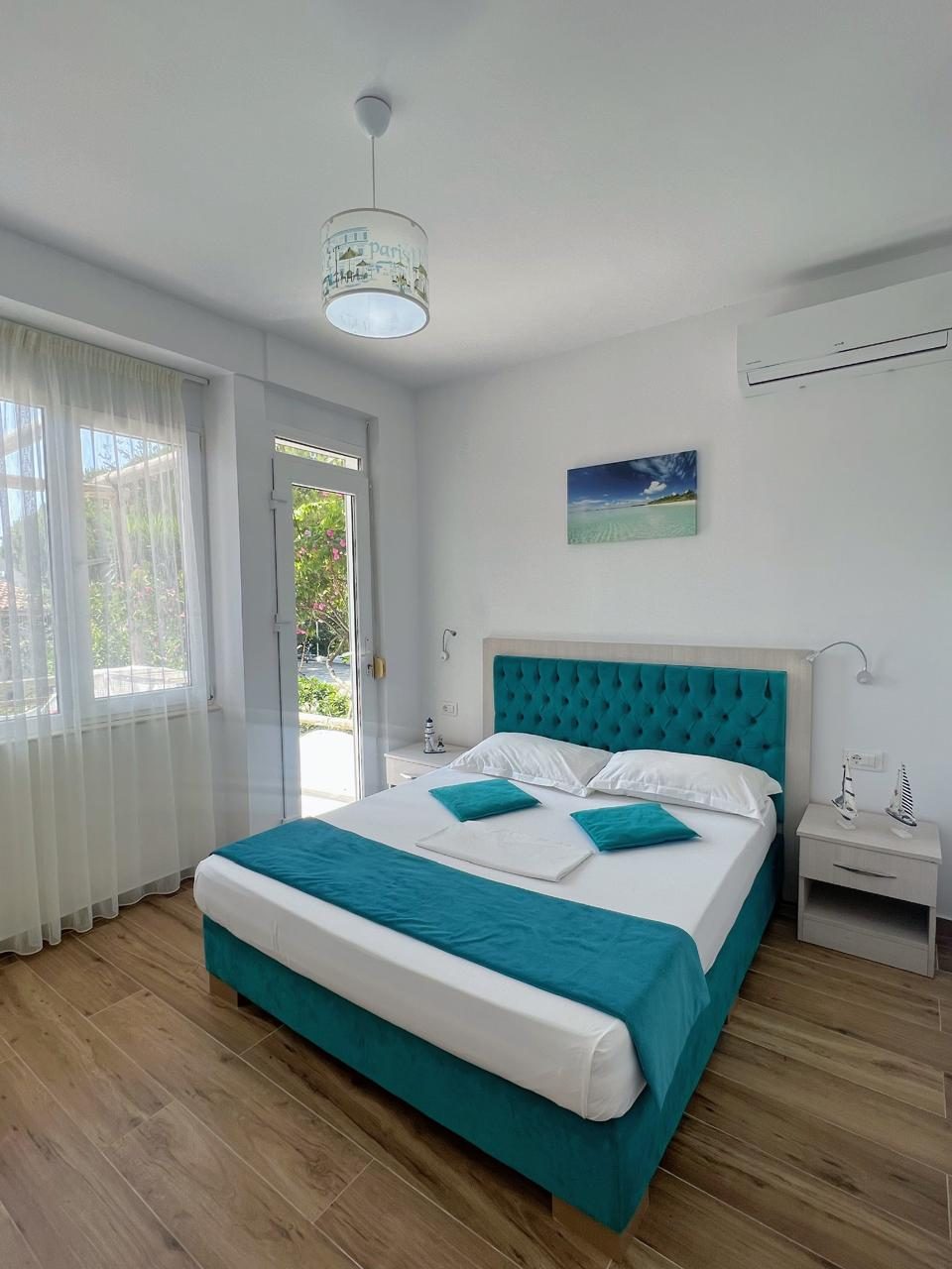 Bedroom with teal headboard opening to the garden