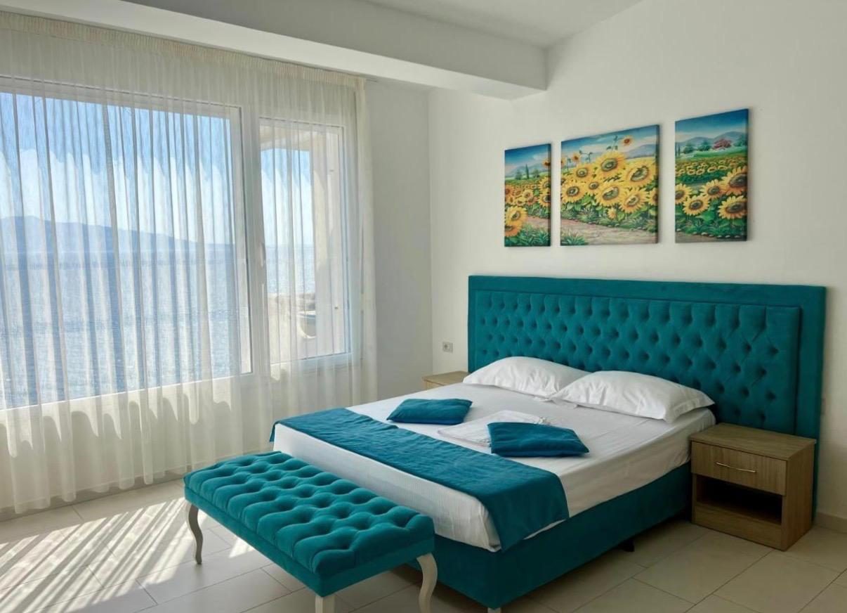 Master bedroom with teal bed and a wide window over the sea