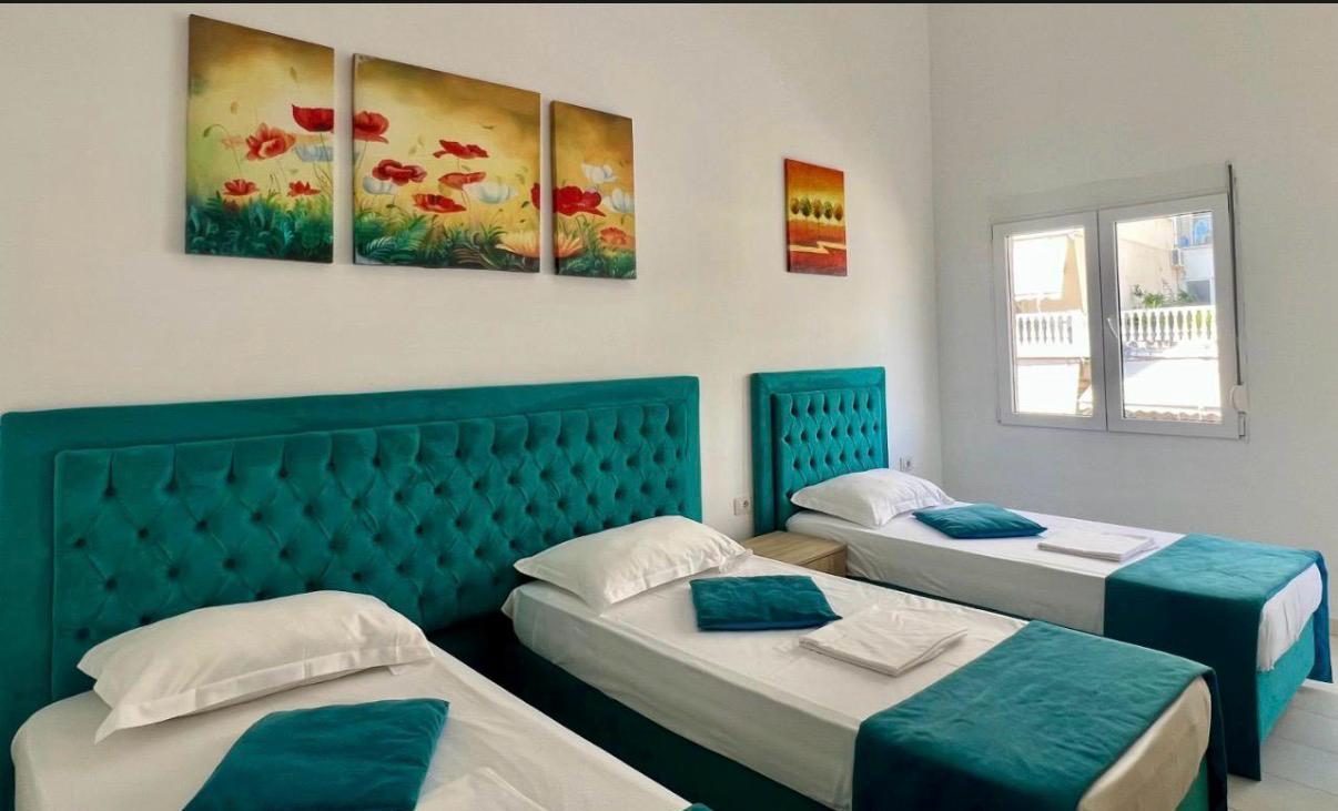 Triple bedroom with teal headboards and poppy paintings