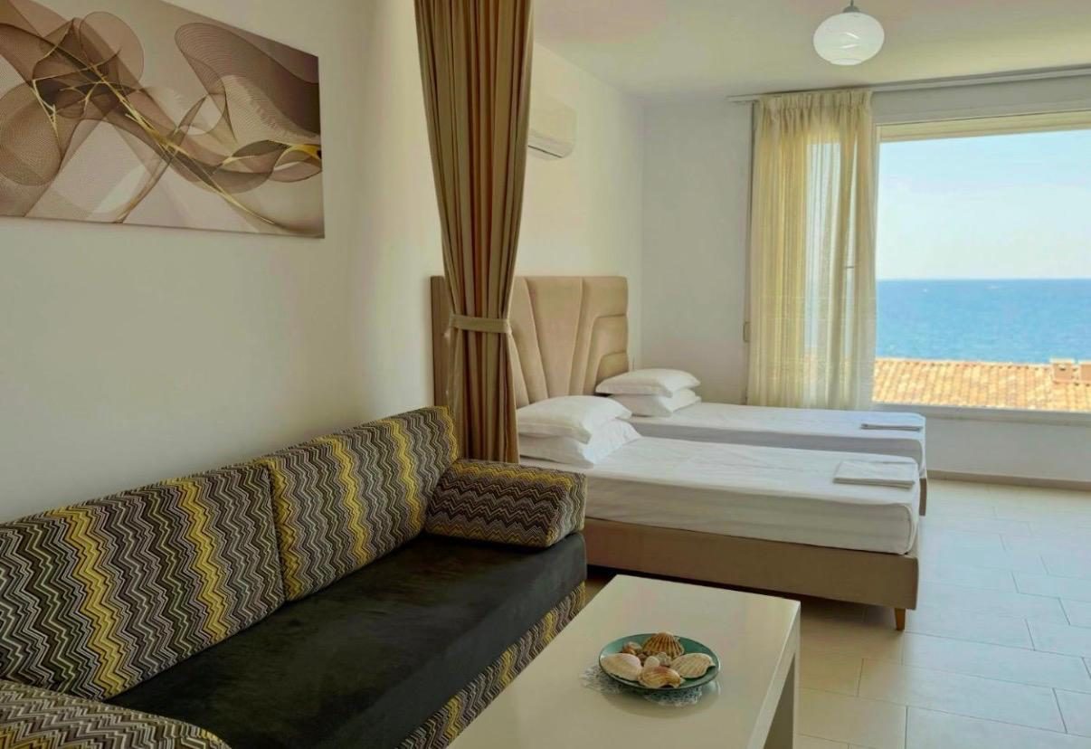 Studio apartment with sofa, beds and a large window over the sea